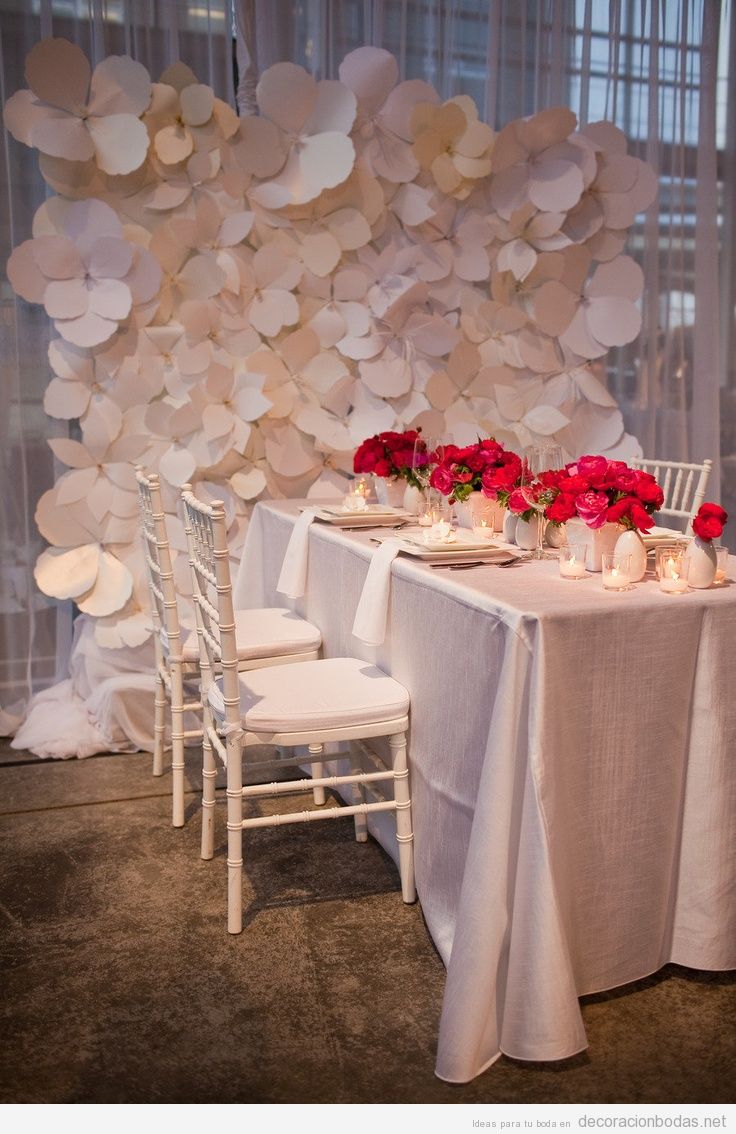 Pared de un salón de bodas decorada con flores blancas de papel