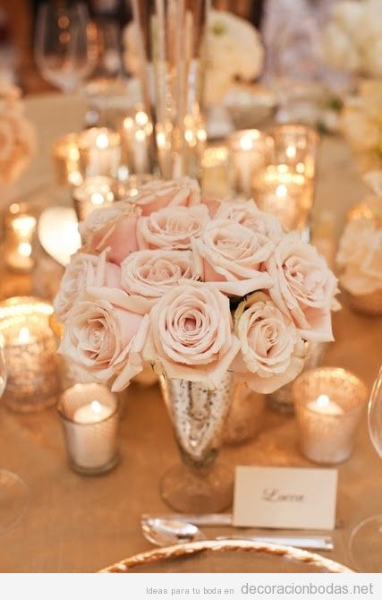 Decoración de mesa de bodas con jarrones de plata vieja, rosas y velas
