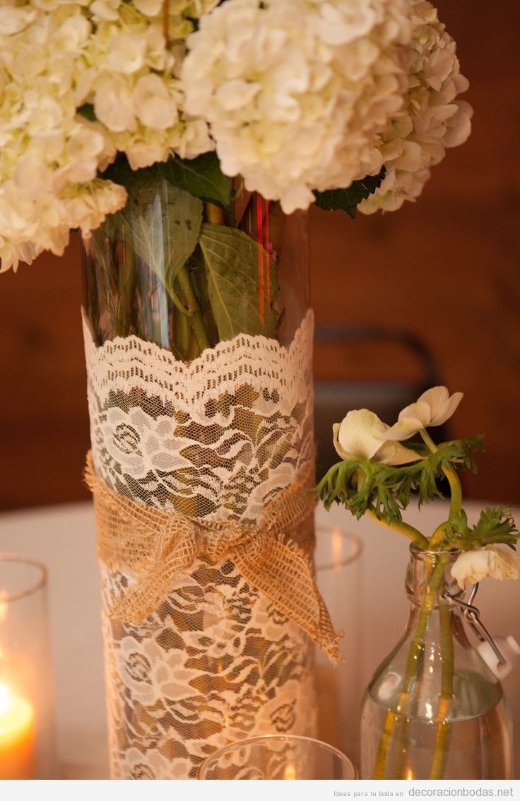 Centro de mesa con jarrones envuelto en encaje y flores blancas