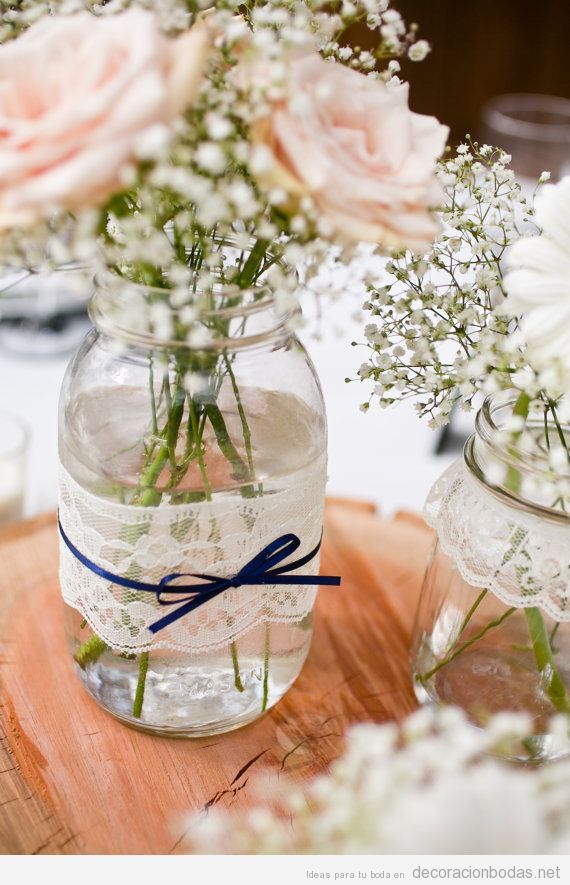 Un bote de cristal adornado con encaje y lazo, centro de mesa DIY ideal para bodas