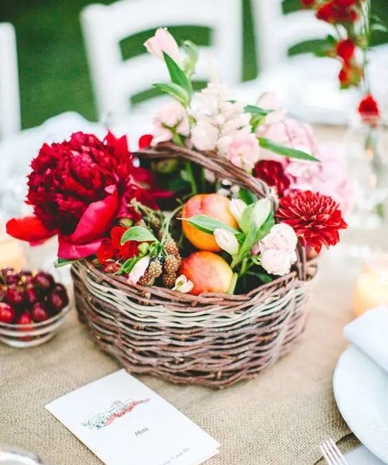 Cesta de mimbre con flores y frutas en el centro de mesa