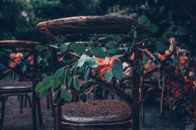 Silla de madera con flores naranjas en boda de otoño en el exterior
